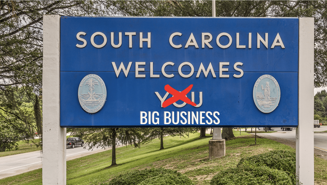 State sign welcoming people to South Carolina. Instead of "South Carolina Welcomes You," the You is crossed out and instead it says "South Carolina Welcomes Big Business"