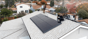 Two men are on top of a roof installing solar panels.