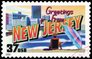 Greetings from New Jersey post card with a person sitting on the beach under an umbrella
