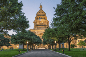 Capitol building in Austin, Texas. Shows government building with green trees on both sides