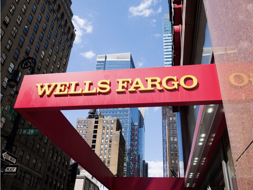 Wells Fargo logo, gold text on a red background, in the middle of an area with skyscrapers.