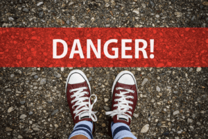 Danger sign and young person's feet wearing what look to be Converse sneakers