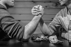 Two male arms arm wrestling in black and white with dollar bills all around.