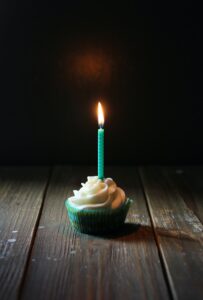 Cupcake with birthday candle on wooden floor