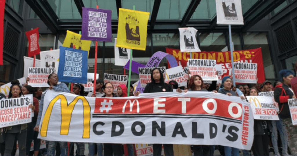 Image of people holding a sign that says #MeToo McDonalds and "Fight for $15"