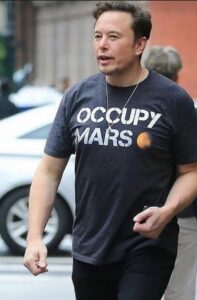 Image of a white man, Elon Musk, wearing an "Occupy Mars" shirt